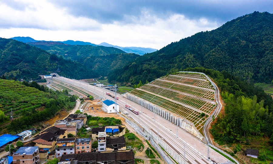 衢宁铁路是一条典型山区铁路。线路经过浙江省仙霞岭、洞宫山及福建省鹫峰山三大山脉，全线高桥长隧工点较多，工程实施难度大。正线新建大中桥144座约51公里，新建隧道94座249公里，桥隧占比79%，全线犹如一条巨大的地铁洞穿山岳。桥梁大跨特殊结构多、高墩桥梁较多，其中洋角大桥最大墩高达113米，相当于28层楼高；全线10公里长度以上隧道有7座，最长的鹫峰山二号隧道，全长17公里；高填深挖路基工点多，其中宁德北站为全线最高深路堑，九级边坡，挖深达71米。图为衢宁铁路上墩（货）站及远处的全线最长隧道鹫峰山二号隧道。