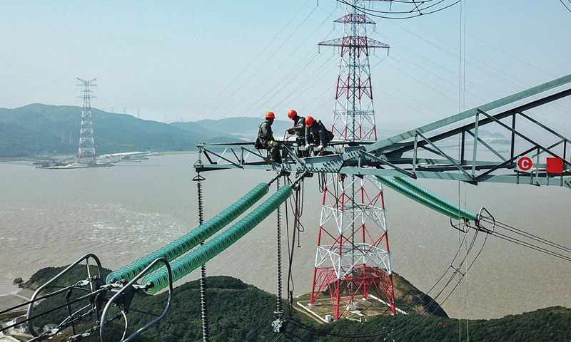 图为10月24日，检修人员在跨海输电高塔上进行检修工作。（新华社记者 徐昱 摄）