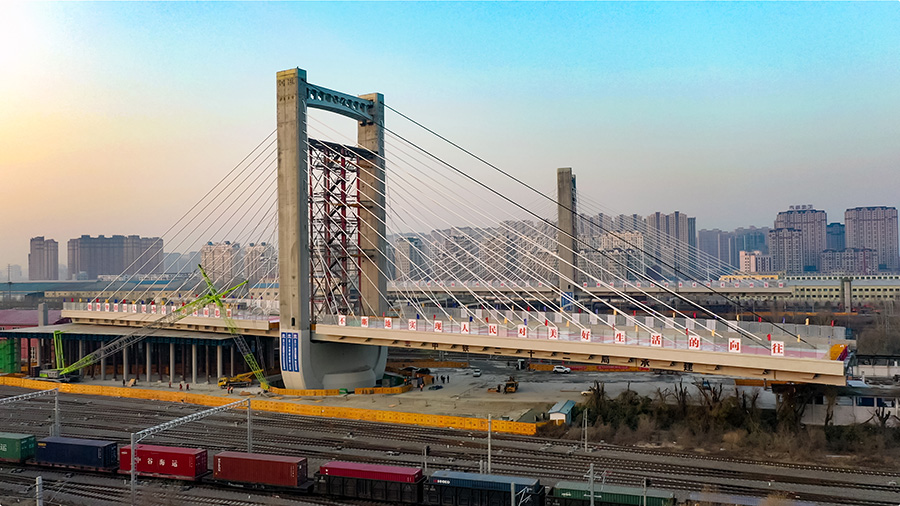 这座桥梁长843米、宽30米，双向6车道，为混凝土现浇连续梁结构，上跨哈尔滨铁路局管内最大路网性编组站哈尔滨南站的48条铁路既有线和1条市政主干道，主跨长198米，两侧边跨各长118米，两座主塔高73.7米。图为缓缓转动的哈西大桥主塔和连续梁。