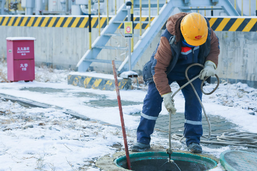化工公司新疆化工工作人员正在清理堵塞的污水井。（贺鹏 摄）