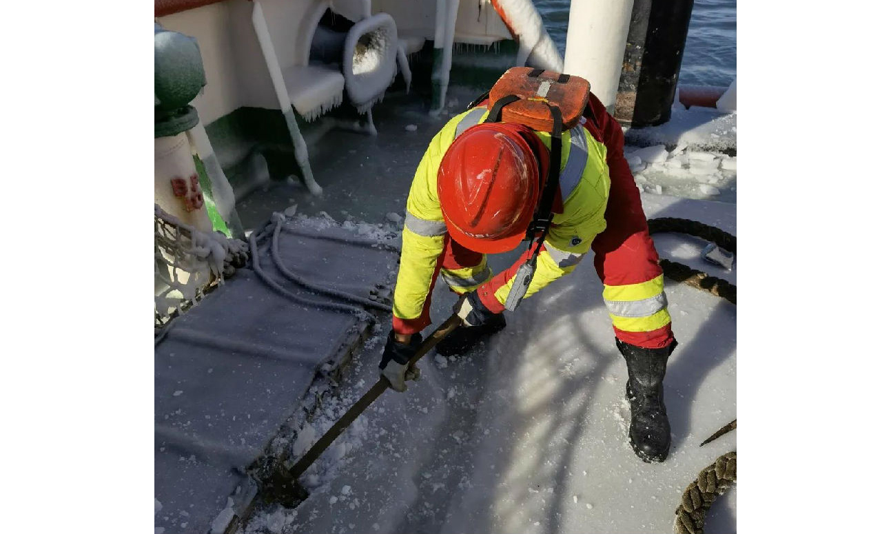 上岸用的跳板被冻在甲板上，工作人员用铁锹一锨一锨把冻冰铲掉。