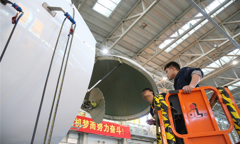 工作人员在中国商飞公司上海飞机制造有限公司总装车间内对C919大型客机102架机进行调整工作。（新华社记者 丁汀 摄）