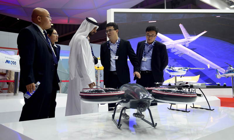 第15届迪拜国际航空展于12日至16日在阿联酋迪拜阿勒马克图姆机场举行。中国航空工业集团等中国企业携无人机、运输机、直升机、战斗机等产品参加展览。中国空军八一飞行表演队也首次受邀参加飞行表演。图为11月13日，在阿联酋迪拜航展上，中国航空工业集团工作人员向参观者介绍产品。（新华社记者 赵丁喆 摄）