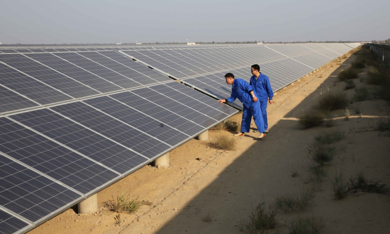 在巴基斯坦旁遮普省焦利斯坦沙漠边缘，有一片颇为壮观的“蓝色海洋”。它静静地把这里丰富的光能转化成电能，造福附近巴哈瓦尔布尔地区的居民。这片“蓝色海洋”就是由中国一冶集团有限公司承建的巴基斯坦300兆瓦光伏电站一期项目。图为12月1日，在巴基斯坦巴哈瓦尔布尔，两名中国工程师在项目园区内检查光伏板。（新华社记者 刘天 摄）