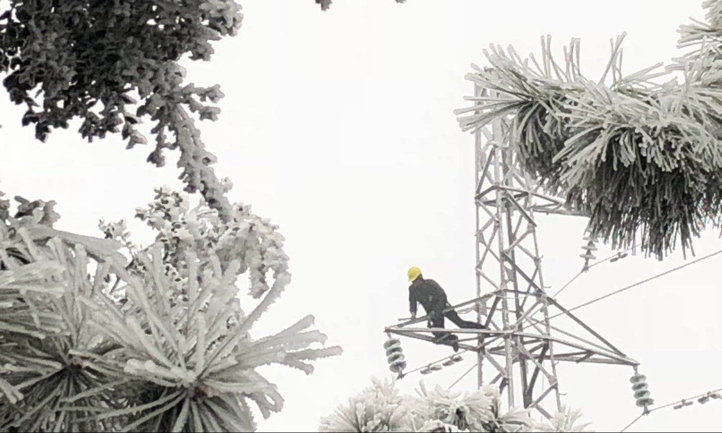 除冰人员登上覆满冰雪的铁塔上敲冰。 （赵英 摄）