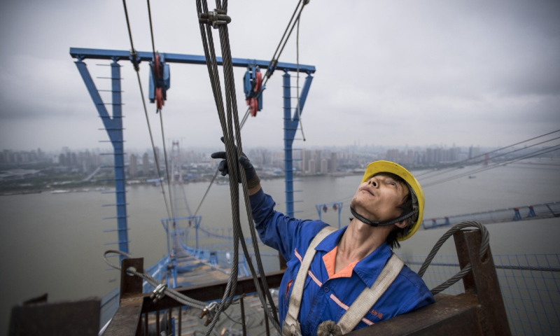 6月8日，来自武汉新洲的34岁工人陈晓辉观察并接收塔吊运送的施工材料。（新华社记者 肖艺九 摄）